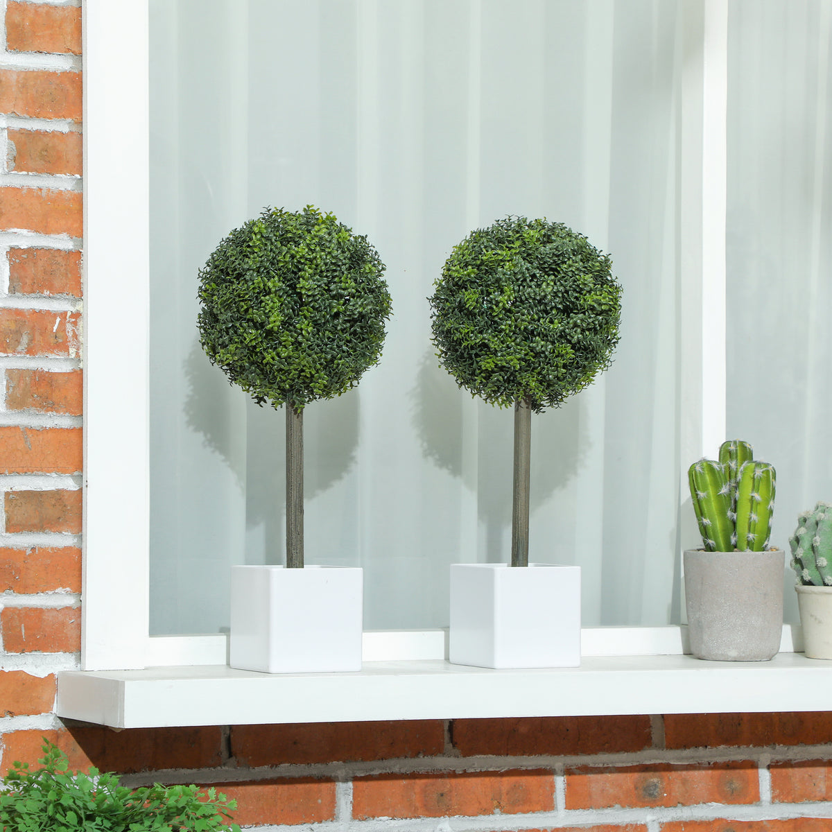 Two boxwood topiary balls on a window ledge