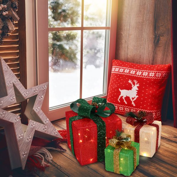 Lighted gift boxes by a snowy window with holiday decor
