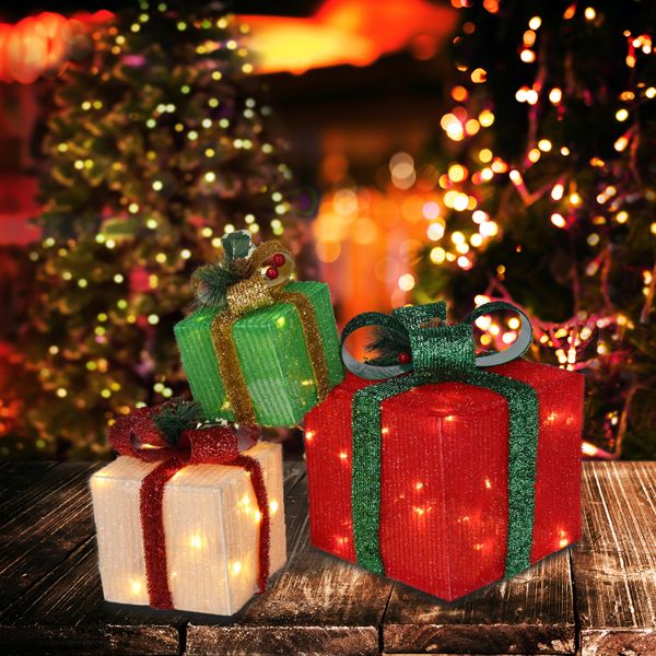 Three lighted Christmas gift boxes glowing in front of a decorated tree